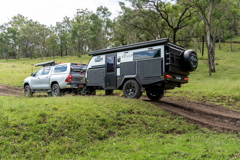 Lifestyle Camper trailer being towed by a truck on a dirt road in a natural setting.