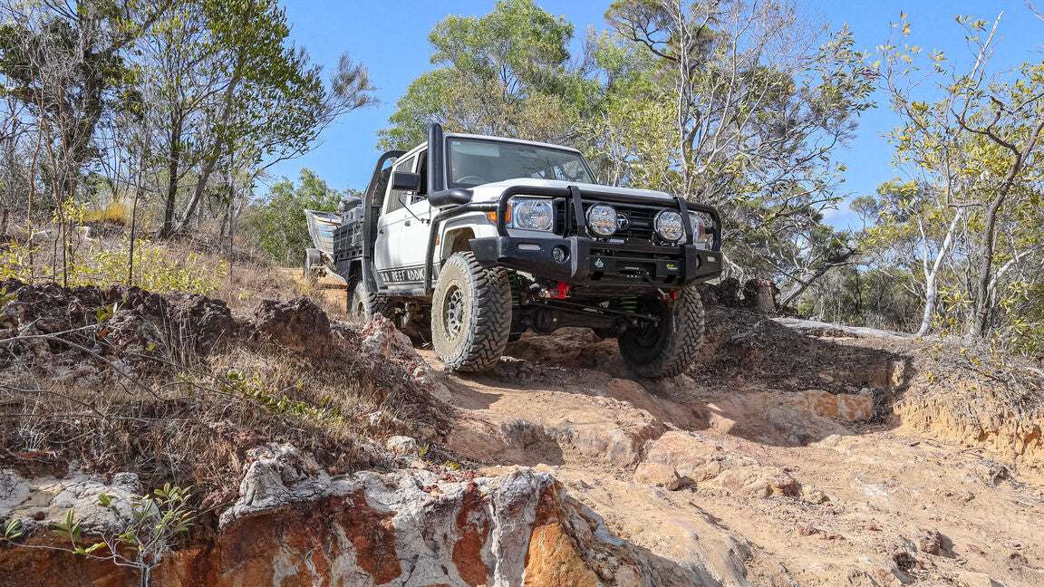 Off-road vehicle navigating a rocky track in a forested area