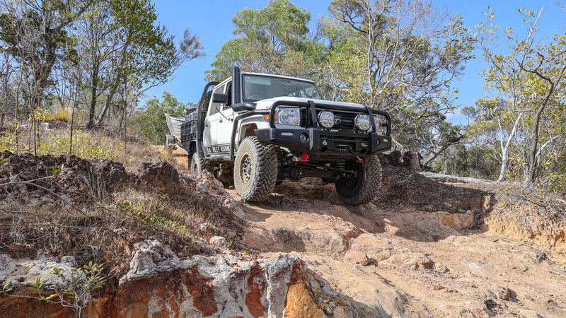 Off-road vehicle navigating a rocky track in a forested area